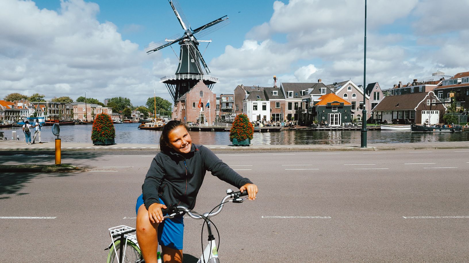 Ragazza su una bici "Girolibero" in un paesaggio tipico olandese con mulino a vento sullo sfondo